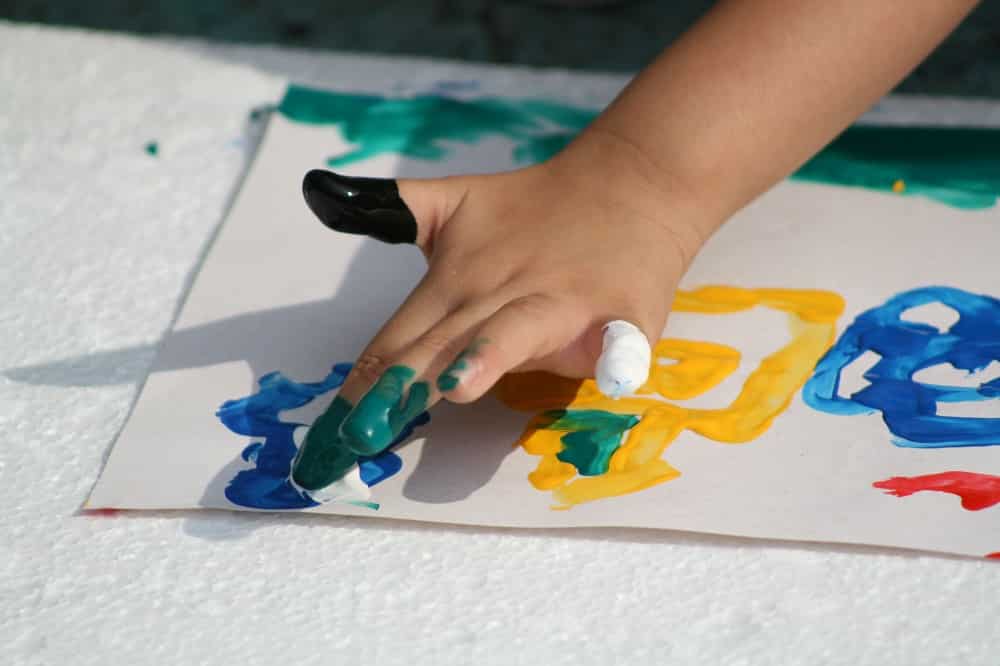 white child's hands finger painting