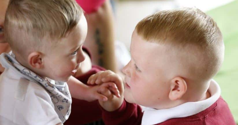 Young school pupil smiling at young baby