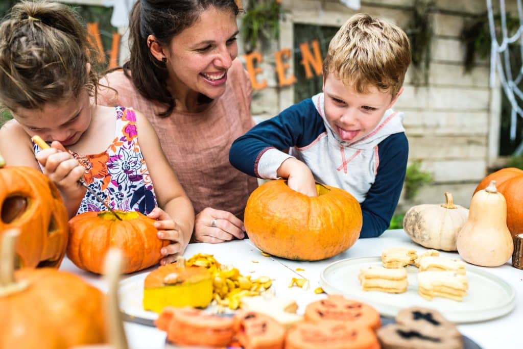 children carving pumpkins safely Dark haired mother with brown haired buy and girl