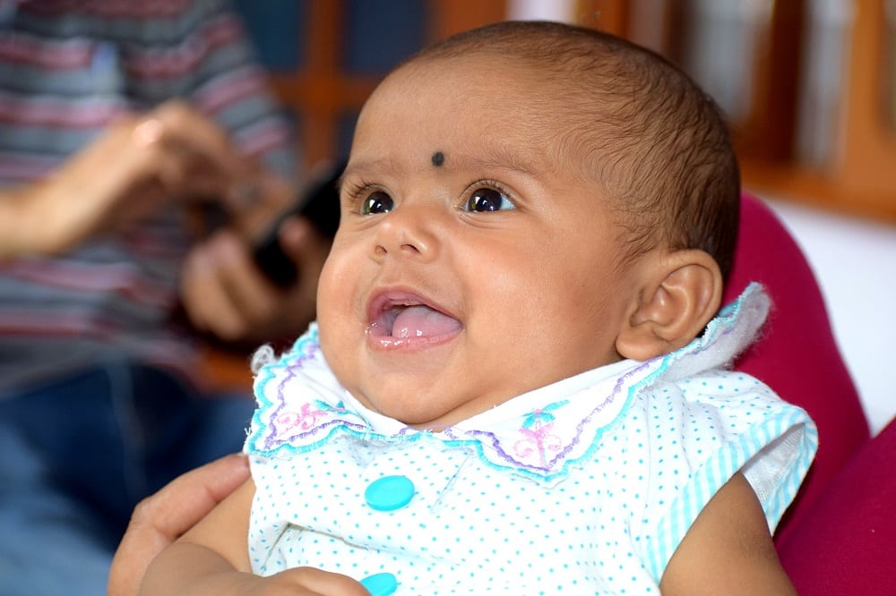 Asian baby smiling at parent