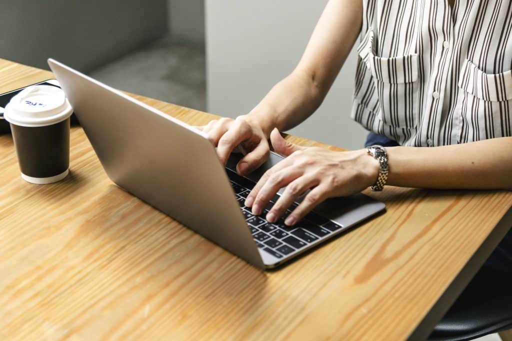 white woman's hands typing on laptop