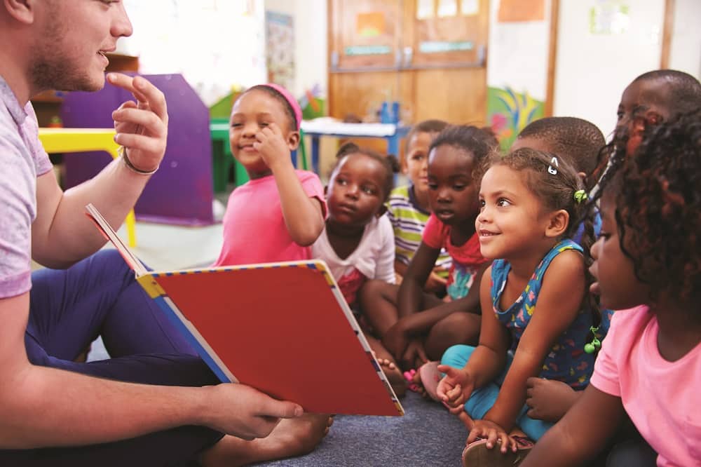 Volunteer teacher reading to a class of preschool kids