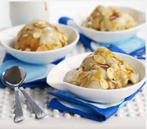 Ice cream with toppings in white bowls on blue and white napkins