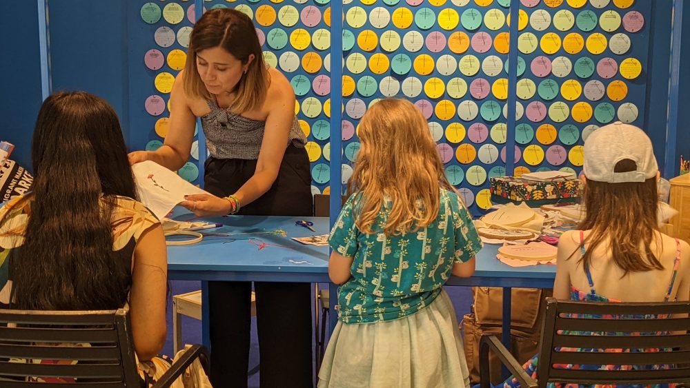 three young girls and facilitator at a table doing a workshop