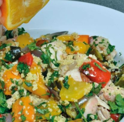 chicken and peppers with cous cous on a white plate