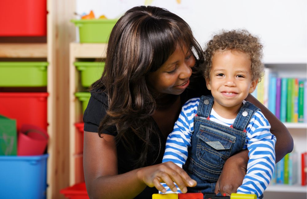 Black mother and mixed race child cuddling and child smiling to camera