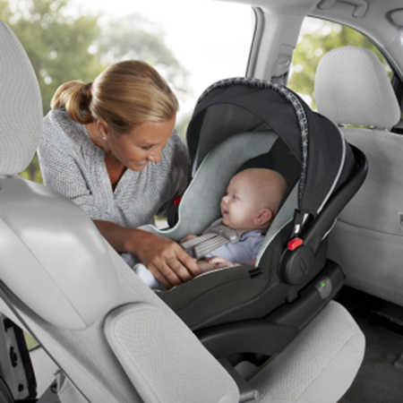 tiny baby in blue outfit being strapped into car seat in the car by Mum