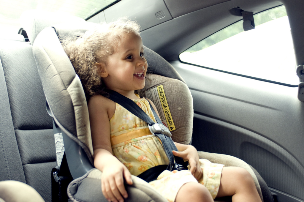 toddler girl in yellow dress strapped into car seat in the car