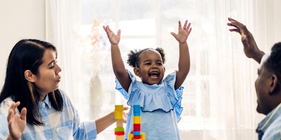 Asian mother, black father and mixed race daughter laughing and having fun building a tower with coloured blocks