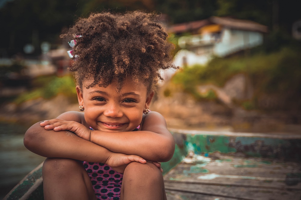 Mixed race young girl in swimsuit with hair up smiling at the camera