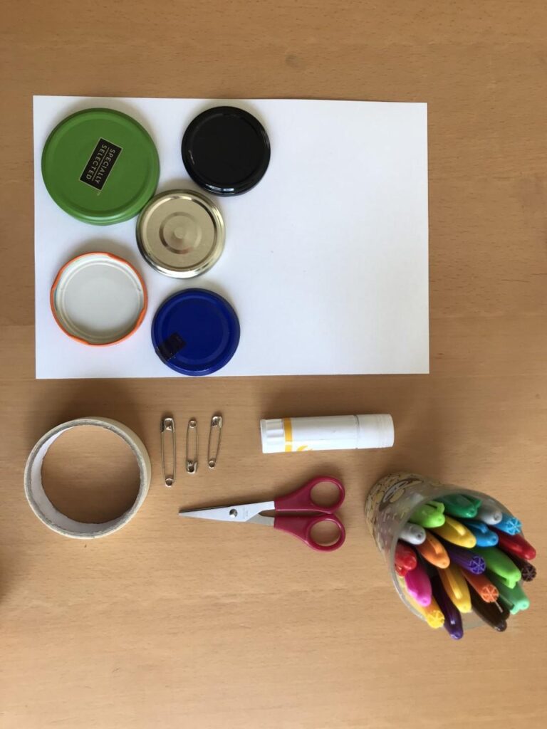 pens, paper, jar lids, and pins to make badges