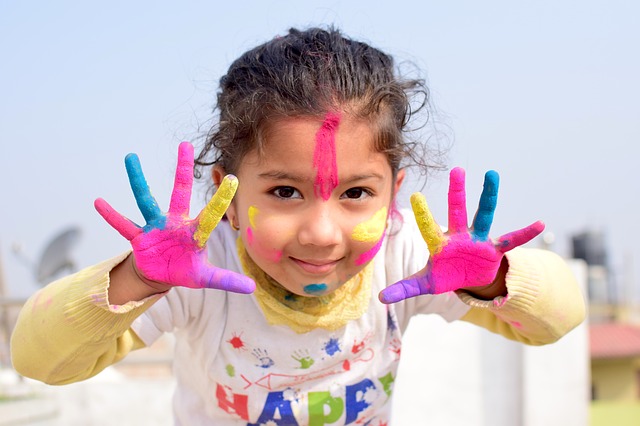 Asian young girl with painted hands and face smiling at the camera